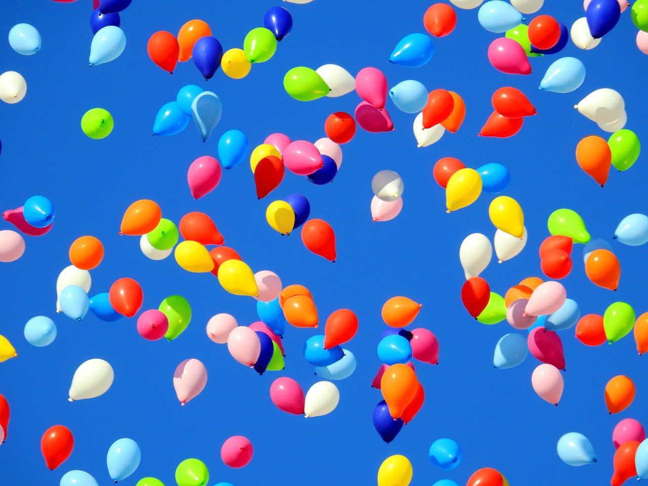 Das Bild zeigt bunte Luftballons am Himmel aufsteigen